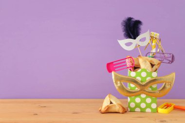 Ahşap masa ve mor arka plan üzerine Purim kutlaması konsepti (Yahudi karnavalı tatili)