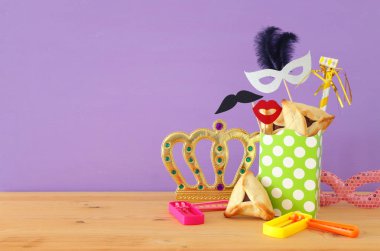 Ahşap masa ve mor arka plan üzerine Purim kutlaması konsepti (Yahudi karnavalı tatili)