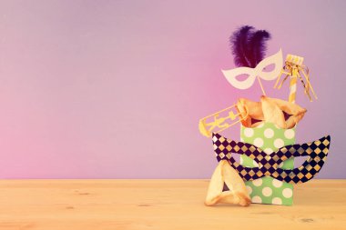 Ahşap masa ve mor arka plan üzerine Purim kutlaması konsepti (Yahudi karnavalı tatili).