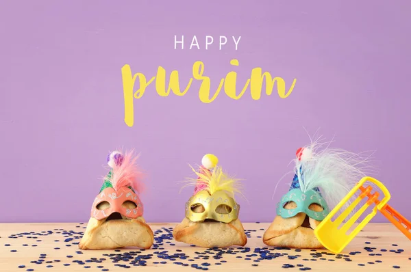普林庆祝概念 犹太狂欢节假日 传统的哈曼塔森饼干 在木桌上戴着可爱的小丑帽和面具 — 图库照片