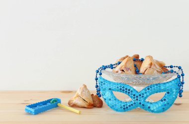 Purim kutlama kavram (Yahudi karnaval tatil) ahşap masa ve beyaz arka plan üzerinde