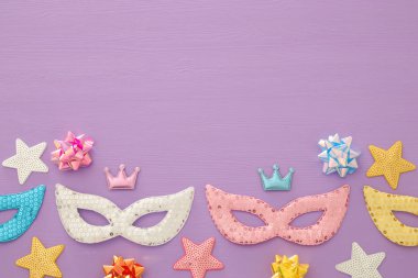 Karnaval parti kutlama kavramı mor ahşap arka plan üzerinde renkli maskeleriyle. Üstten görünüm. Düz yatıyordu