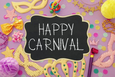 Karnaval parti kutlama kavramı maskesi ve mor ahşap arka plan üzerinde renkli parti aksesuarları ile. Üstten görünüm. Düz yatıyordu