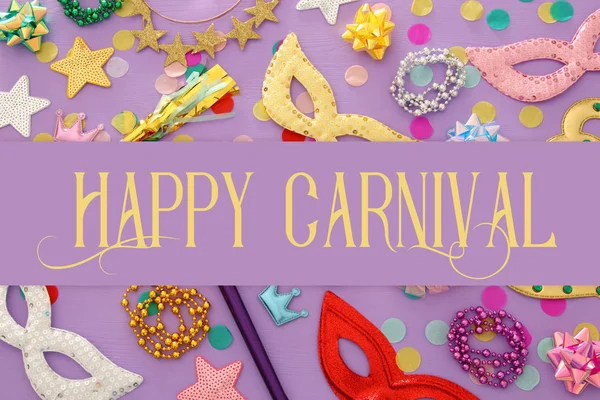 carnival party celebration concept with mask and colorful party accessories over purple wooden background. Top view. Flat lay