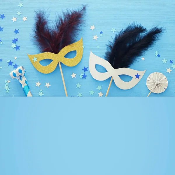 carnival party celebration concept with elegant gold mask on stick over blue wooden background and stars. Top view