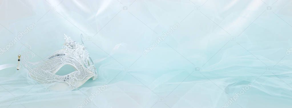 Banner of elegant and delicate white lace venetian mask over mint chiffon background