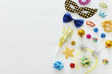 Karnaval parti kutlama kavramı maskesi ve beyaz ahşap arka plan üzerinde renkli parti aksesuarları ile. Üstten görünüm. Düz yatıyordu