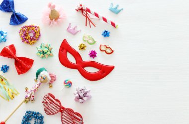 Karnaval parti kutlama kavramı maskesi ve beyaz ahşap arka plan üzerinde renkli parti aksesuarları ile. Üstten görünüm. Düz yatıyordu