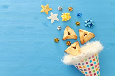 Purim kutlama kavramı (Yahudi karnaval tatil). Geleneksel hamantaschen çerezler üzerinde mavi ahşap masa