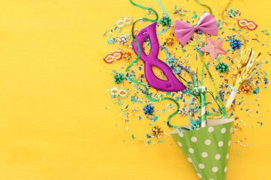 Parti renkli konfeti ve palyaço şapkası sarı ahşap zemin üzerinde. Üstten görünüm, düz yatıyordu