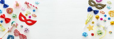 Karnaval parti kutlama kavramı maskesi ve beyaz ahşap arka plan üzerinde renkli parti aksesuarları ile. Üstten görünüm. Düz yatıyordu