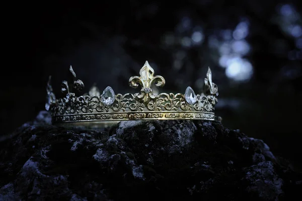 gizemli ve büyülü fotoğraf altın Kral taç İngiltere woods veya alan yatay ışık parlama ile yosun kaplı taş üzerinde. Ortaçağ Dönemi kavramı