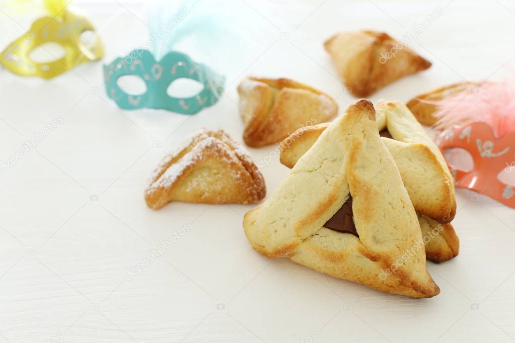 Purim celebration concept (jewish carnival holiday). Traditional hamantaschen cookies over white wooden table