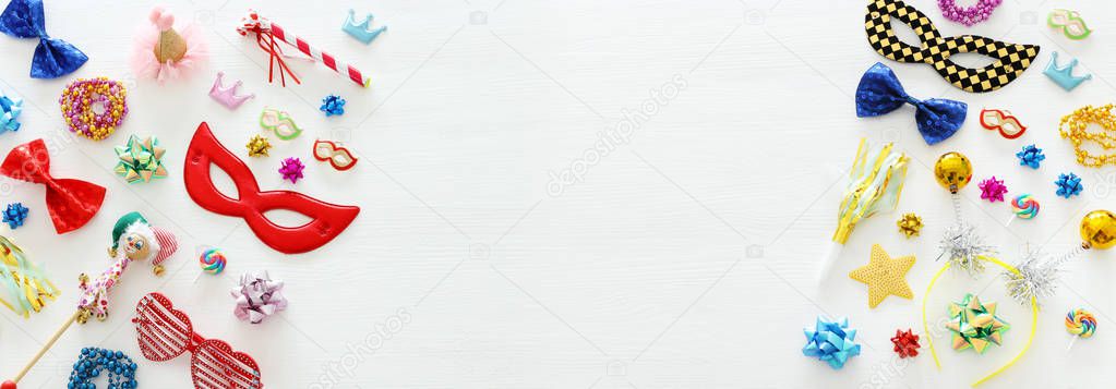 carnival party celebration concept with mask and colorful party accessories over white wooden background. Top view. Flat lay