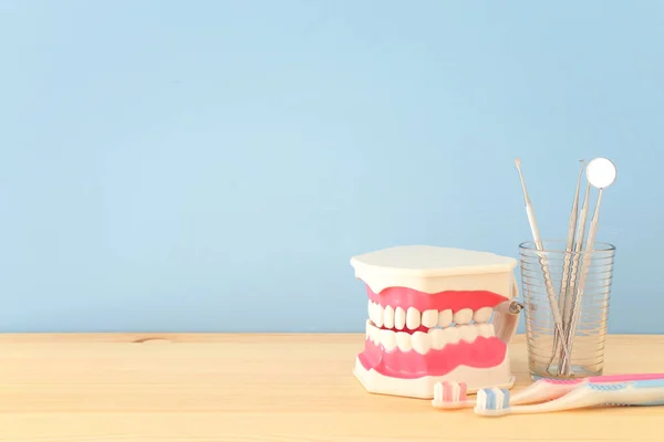 Dental care tools use for dentist and plastic teeth model in the clinic. Wooden blue background. — Stock Photo, Image
