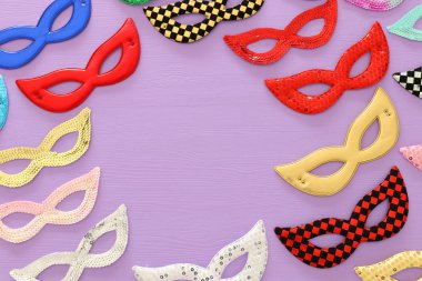 Karnaval parti kutlama kavramı mor ahşap arka plan üzerinde renkli maske koleksiyonu ile. Üstten görünüm. Düz yatıyordu.