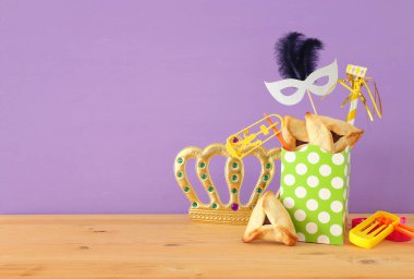 Ahşap masa ve mor arka plan üzerine Purim kutlaması konsepti (Yahudi karnavalı tatili)