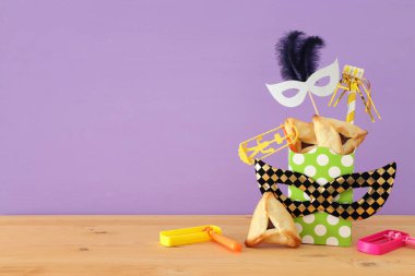 Ahşap masa ve mor arka plan üzerine Purim kutlaması konsepti (Yahudi karnavalı tatili)