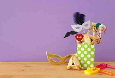 Ahşap masa ve mor arka plan üzerine Purim kutlaması konsepti (Yahudi karnavalı tatili)