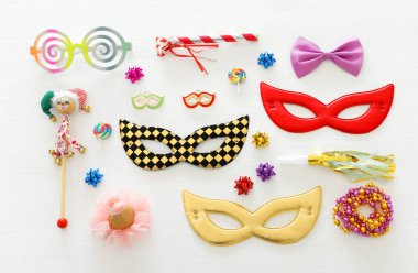 Karnaval parti kutlama kavramı maskesi ve beyaz ahşap arka plan üzerinde renkli parti aksesuarları ile. Üstten görünüm