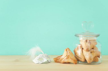Purim kutlama kavramı (Yahudi karnaval tatil). Geleneksel hamantaschen çerezler ve maskeyi ahşap masa üzerine
