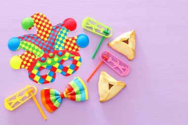 Purim kutlama kavramı (Yahudi karnaval tatil) ahşap mor arka plan üzerinde renkli joker veya Palyaço maskesi