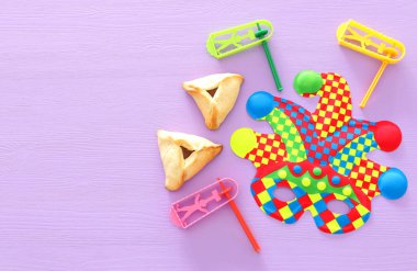 Purim kutlama kavramı (Yahudi karnaval tatil) ahşap mor arka plan üzerinde renkli joker veya Palyaço maskesi