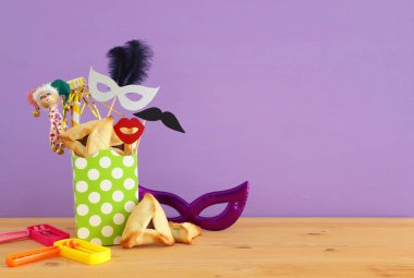Ahşap masa ve mor arka plan üzerine Purim kutlaması konsepti (Yahudi karnavalı tatili)