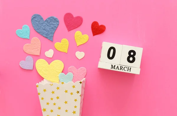 ピンクの木製の背景にカラフルな心の横に木製の 日カレンダー — ストック写真