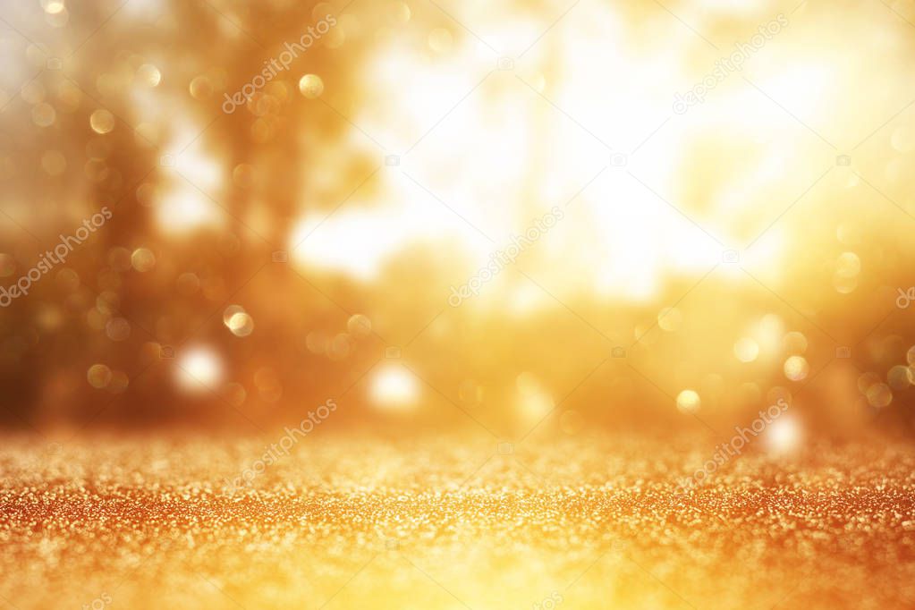 blurred abstract photo of light burst among trees and glitter golden bokeh lights