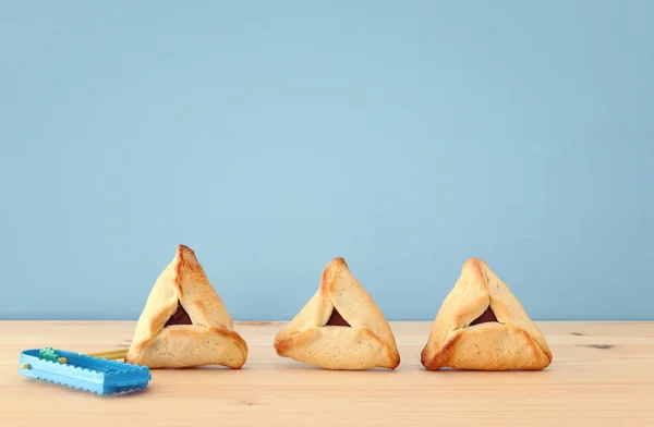 Concetto di celebrazione Purim (festa di carnevale ebraica). biscotti hamantaschen tradizionali sopra tavolo di legno e sfondo blu . — Foto Stock