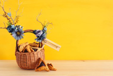 Purim kutlama kavramı (Yahudi karnaval tatil) geleneksel hamantasch kurabiye ve geyik boynuzları çiçek dekorasyonu ile ahşap masa üzerinde