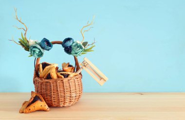 Purim kutlama kavramı (Yahudi karnaval tatil) geleneksel hamantasch kurabiye ve geyik boynuzları çiçek dekorasyonu ile ahşap masa üzerinde