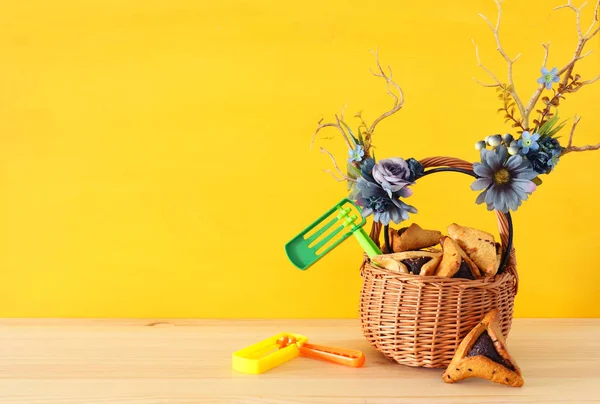Purim kutlama kavramı (Yahudi karnaval tatil) geleneksel hamantasch kurabiye ve geyik boynuzları çiçek dekorasyonu ile ahşap masa üzerinde