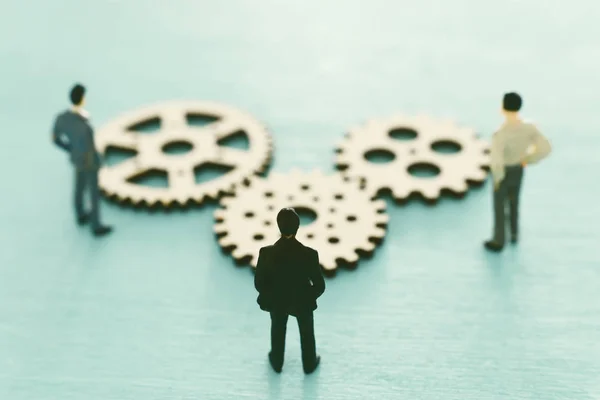 Miniature people looking at cogwheel in set of gears mechanism. Problem solving concept — Stock Photo, Image