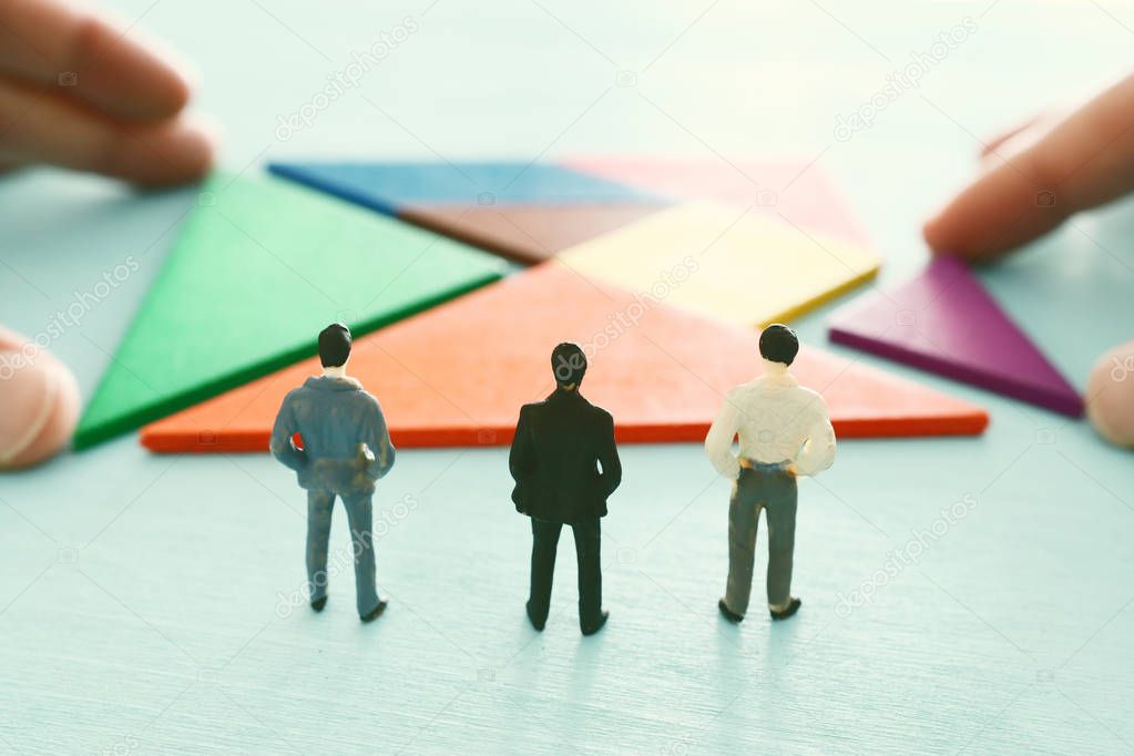tangram puzzle blocks with miniature people over wooden table ,human resources, problem solving and management concept