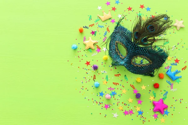 Concetto di festa di carnevale con maschera su sfondo verde in legno. Vista dall'alto. Posa piatta — Foto Stock