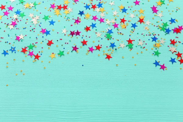 Partij kleurrijke confetti over lichte pastel blauwe houten achtergrond. Bovenaanzicht, plat lag — Stockfoto