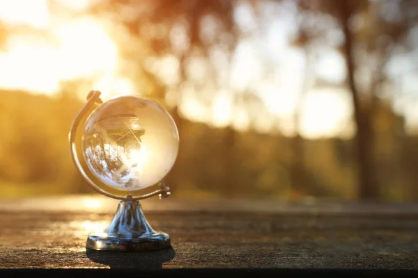 Petit globe de cristal devant le coucher du soleil. concept de voyage et enjeux mondiaux — Photo