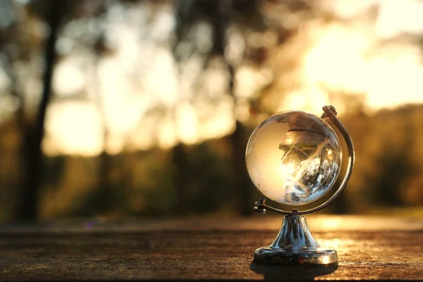 Piccolo globo di cristallo davanti al tramonto. concetto di viaggio e questioni globali — Foto Stock