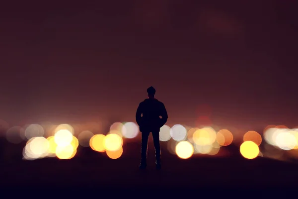 Silhouette eines Miniaturmannes, der die Lichter der Stadt in der Nähe betrachtet — Stockfoto