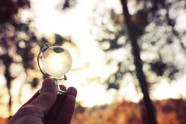 Kleine crystal globe voor zonsondergang. reizen en mondiale vraagstukken concept — Stockfoto