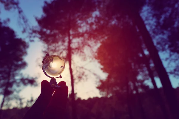 Petit globe de cristal devant le coucher du soleil. concept de voyage et enjeux mondiaux — Photo