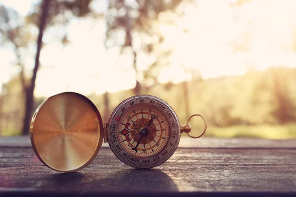 Kompas přes dřevěný stůl v západu slunce světlo — Stock fotografie