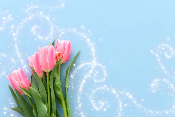 パステル ブルーの木製の背景のピンクの花束。平面図です。キラキラ オーバーレイ — ストック写真