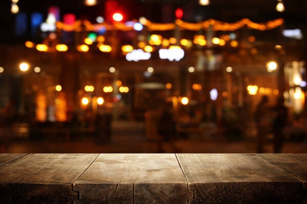 Изображение деревянного стола перед абстрактным размытым фоном ресторана
