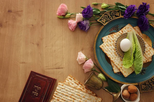 Pesah Feier Konzept (jüdischer Pessach-Feiertag). Übersetzung für hebräischen Text über Platte (matzah) matza und traditionelles Buch mit hebräischem Text: Pessach haggadah (Passahgeschichte)) — Stockfoto