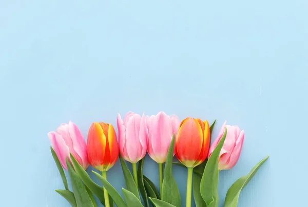 Bouquet of orange and pink tulips over pastel blue wooden background. Top view — Stock Photo, Image