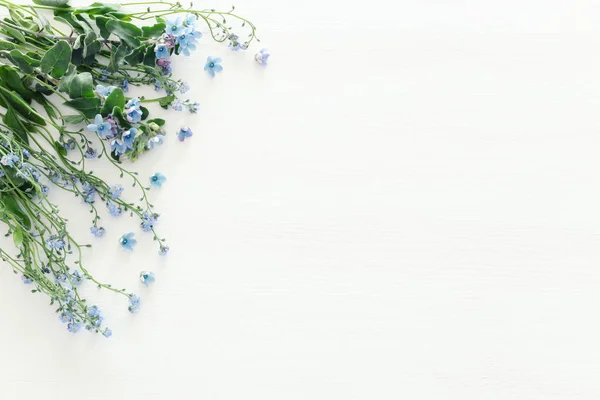 Bouquet primaverile di fiori blu e delicati su sfondo bianco in legno. vista dall'alto, posizione piatta — Foto Stock