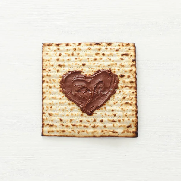 Concepto de celebración de Pesah (fiesta judía de Pascua) con corazón de chocolate sobre matzah. Vista superior plano laico — Foto de Stock